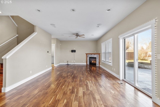 unfurnished living room featuring a fireplace, visible vents, ceiling fan, wood finished floors, and baseboards