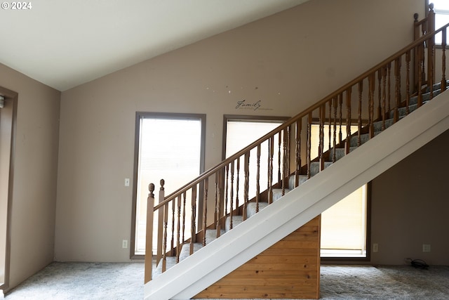 staircase featuring lofted ceiling, a wealth of natural light, and carpet flooring