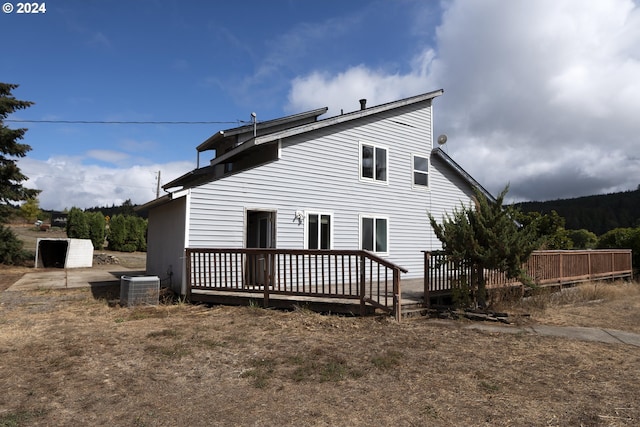 rear view of property featuring central AC unit, a storage shed, and a deck