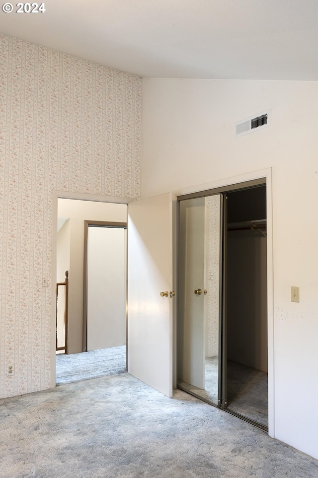 unfurnished bedroom featuring lofted ceiling, carpet flooring, and a closet