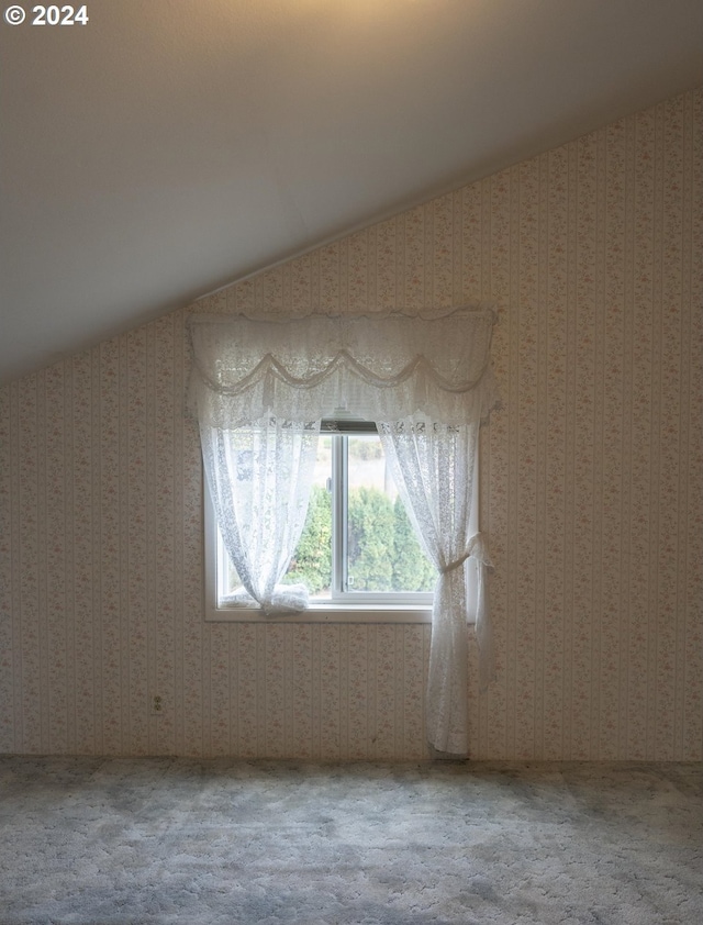 carpeted spare room with vaulted ceiling