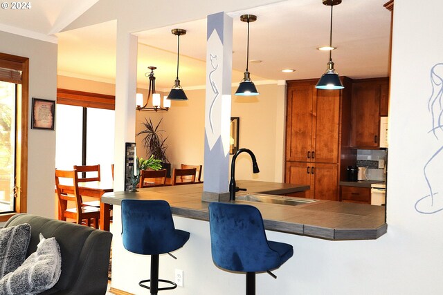 kitchen featuring pendant lighting, tile counters, a breakfast bar, kitchen peninsula, and sink