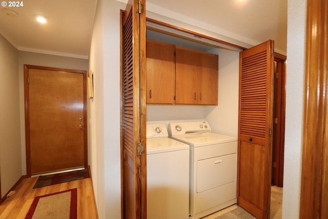 laundry area with cabinets, ornamental molding, washer and clothes dryer, and light hardwood / wood-style flooring