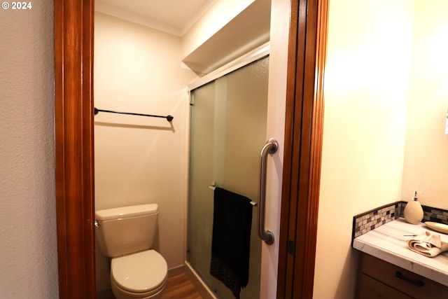 bathroom featuring a shower with shower door, toilet, ornamental molding, and vanity