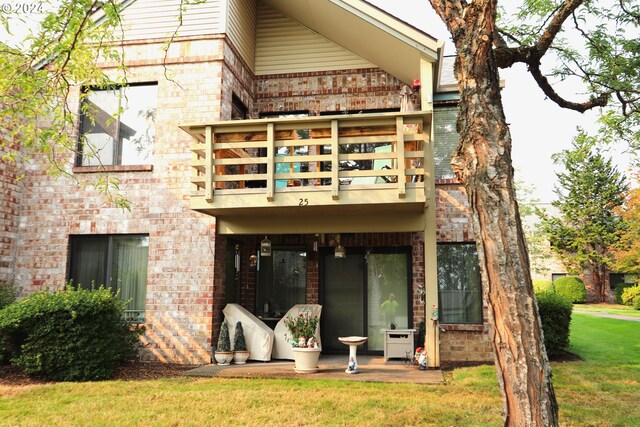 back of house featuring a balcony and a lawn