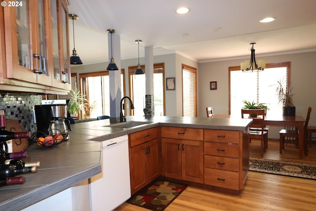 kitchen featuring light wood-type flooring, a healthy amount of sunlight, kitchen peninsula, and sink