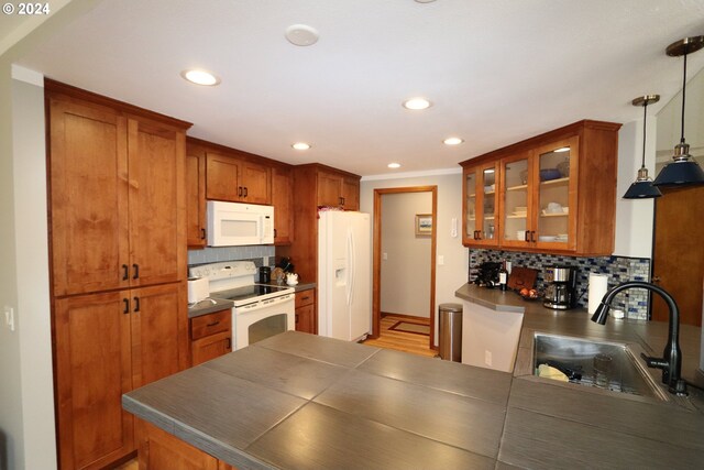 kitchen with white appliances, pendant lighting, light hardwood / wood-style flooring, kitchen peninsula, and sink