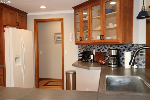 kitchen featuring decorative light fixtures, backsplash, crown molding, sink, and white fridge with ice dispenser