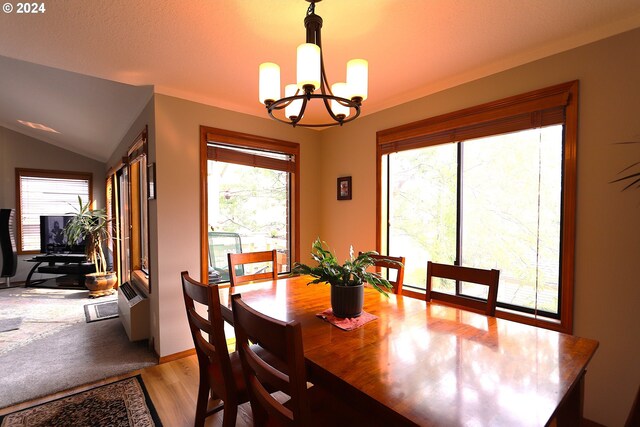 dining area featuring light wood-type flooring, lofted ceiling, and a chandelier