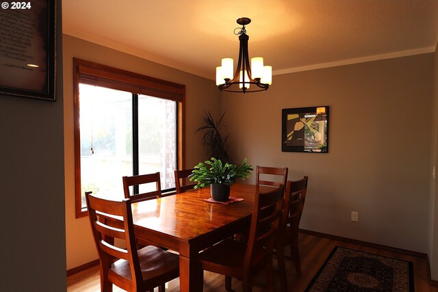 dining area with ornamental molding, wood-type flooring, and an inviting chandelier