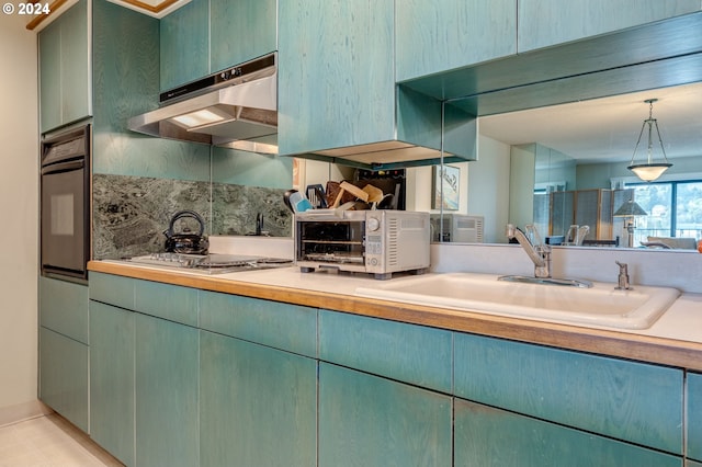 kitchen featuring sink, oven, stainless steel gas cooktop, and hanging light fixtures