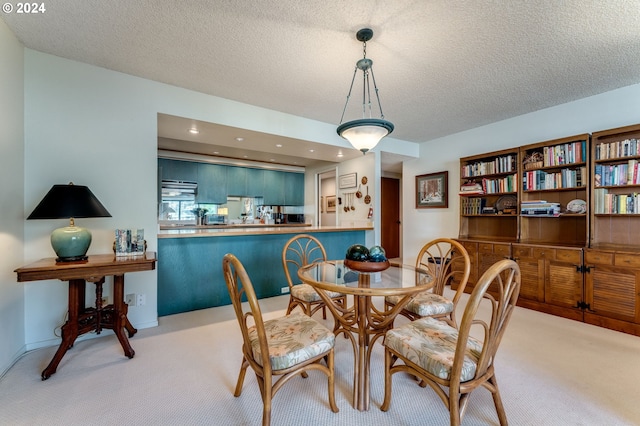 dining area featuring light carpet and a textured ceiling