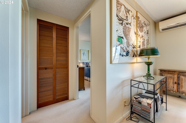 hallway featuring a wall mounted air conditioner, light carpet, and a textured ceiling