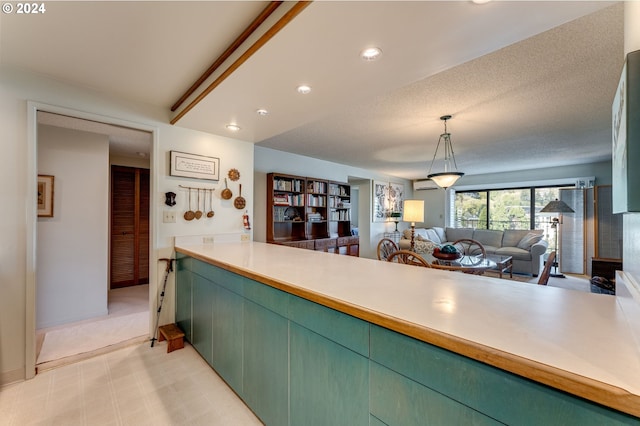 kitchen with a wall mounted AC, green cabinets, and a textured ceiling