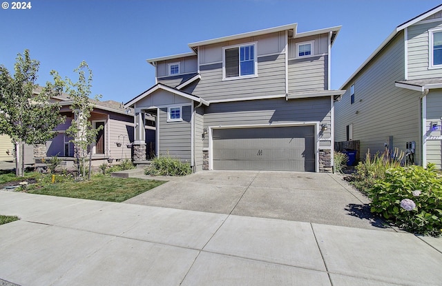 view of front of home featuring an attached garage, stone siding, and concrete driveway