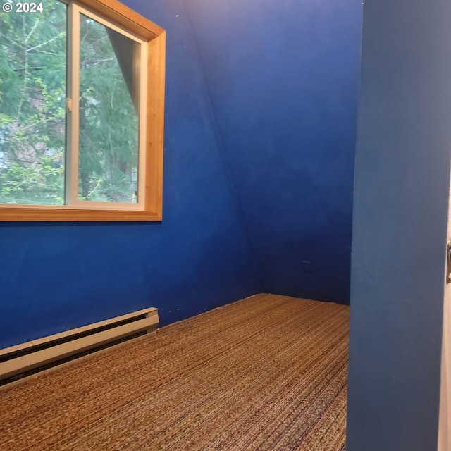 carpeted spare room with a baseboard heating unit