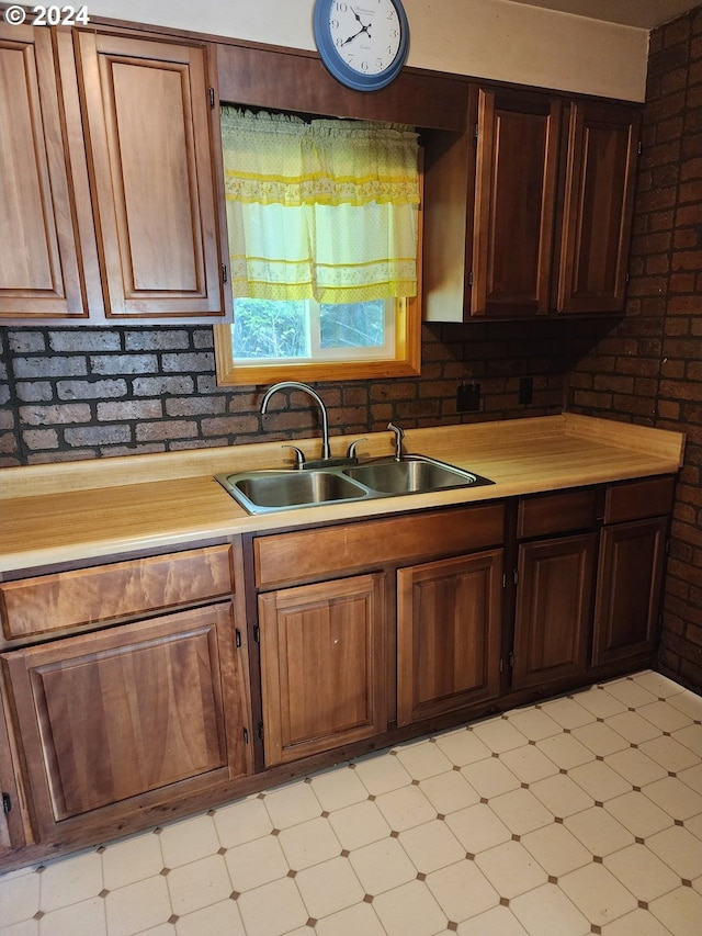 kitchen featuring brick wall and sink