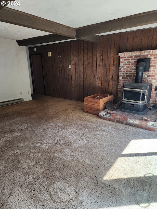 living room featuring beamed ceiling, a wood stove, carpet, wooden walls, and a baseboard heating unit