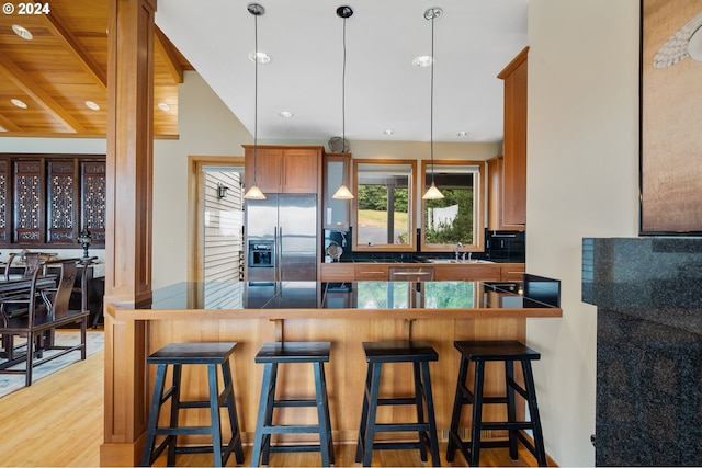 kitchen featuring light hardwood / wood-style flooring, sink, stainless steel fridge with ice dispenser, kitchen peninsula, and vaulted ceiling