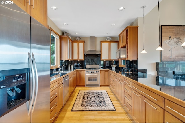 kitchen featuring wall chimney range hood, backsplash, appliances with stainless steel finishes, and hanging light fixtures