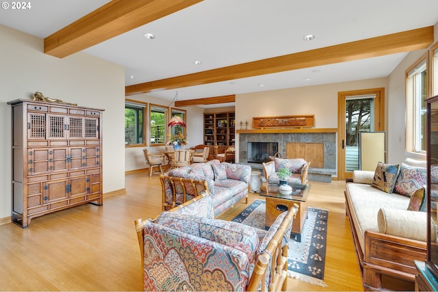 living room with a fireplace, beam ceiling, and light hardwood / wood-style floors