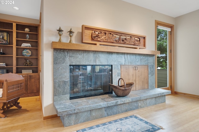 details with baseboards, a tiled fireplace, and wood finished floors