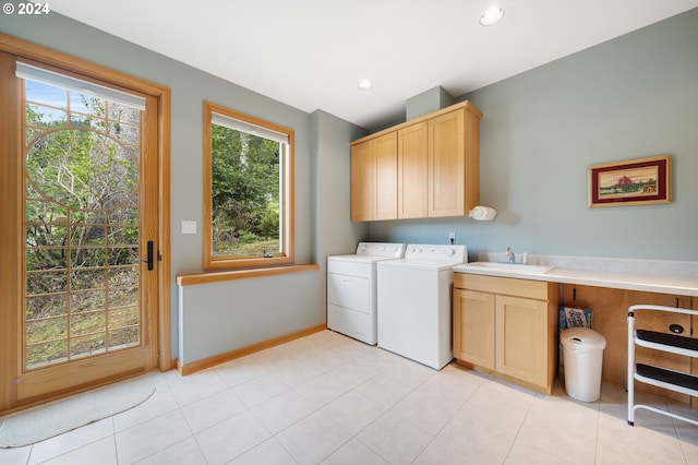 clothes washing area featuring light tile patterned floors, washing machine and dryer, sink, and cabinets