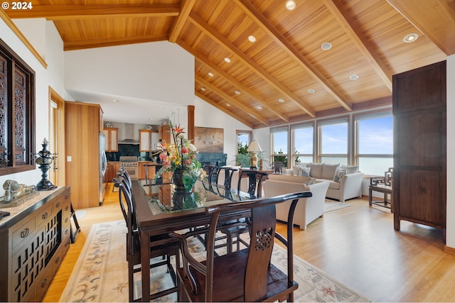 dining space with beam ceiling, light hardwood / wood-style floors, high vaulted ceiling, a water view, and wood ceiling