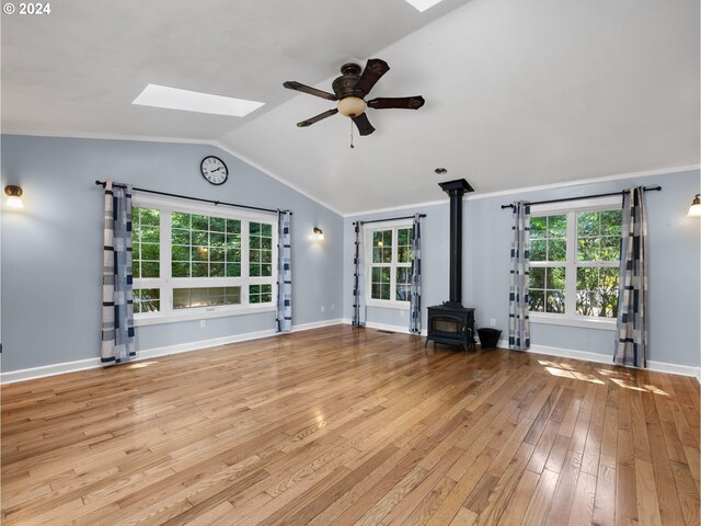 unfurnished living room featuring a wealth of natural light, crown molding, light wood-type flooring, and a wood stove