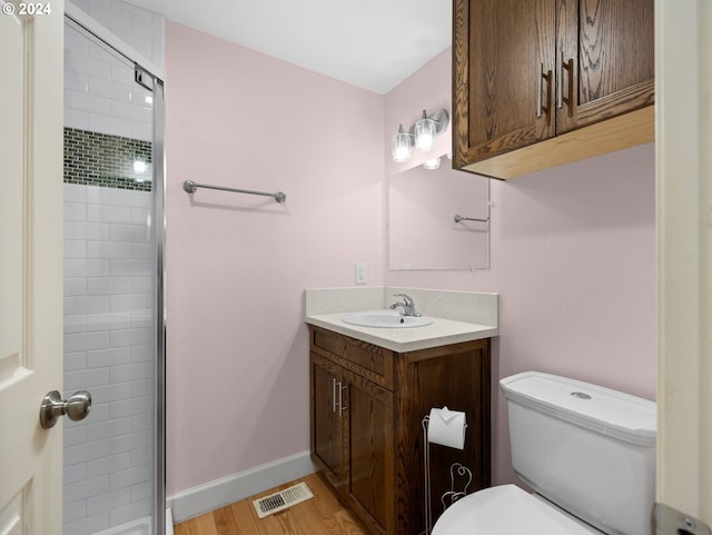 bathroom with toilet, a shower with door, vanity, and wood-type flooring