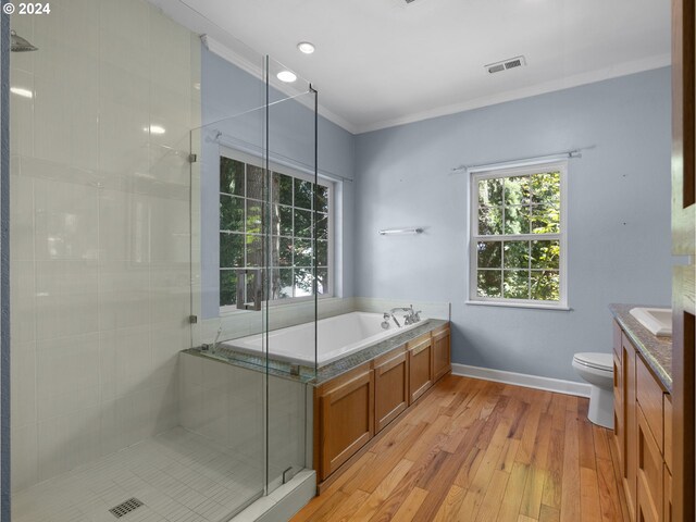 full bathroom with ornamental molding, vanity, independent shower and bath, wood-type flooring, and toilet