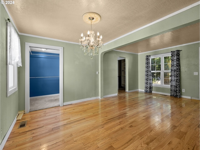 unfurnished room with arched walkways, ornamental molding, hardwood / wood-style flooring, and visible vents