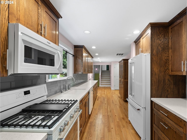 kitchen featuring sink, light hardwood / wood-style flooring, premium appliances, and tasteful backsplash