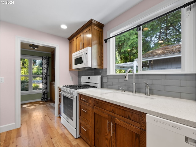 kitchen featuring sink, plenty of natural light, backsplash, and white appliances