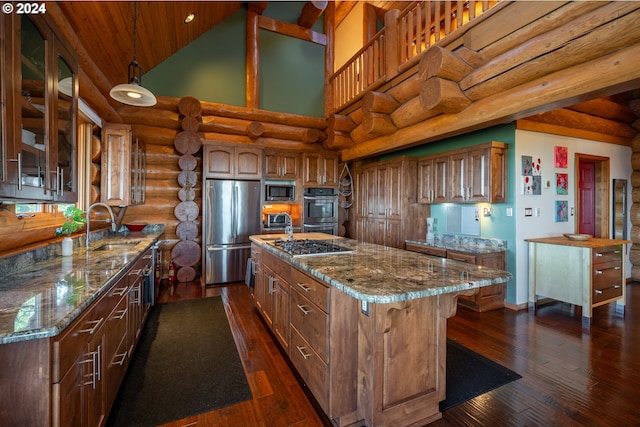 kitchen with appliances with stainless steel finishes, a kitchen island, sink, and dark hardwood / wood-style flooring