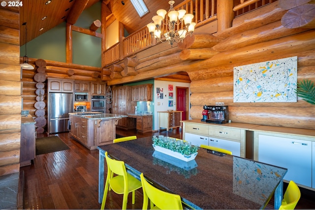 kitchen with appliances with stainless steel finishes, high vaulted ceiling, a kitchen island, dark hardwood / wood-style flooring, and a chandelier