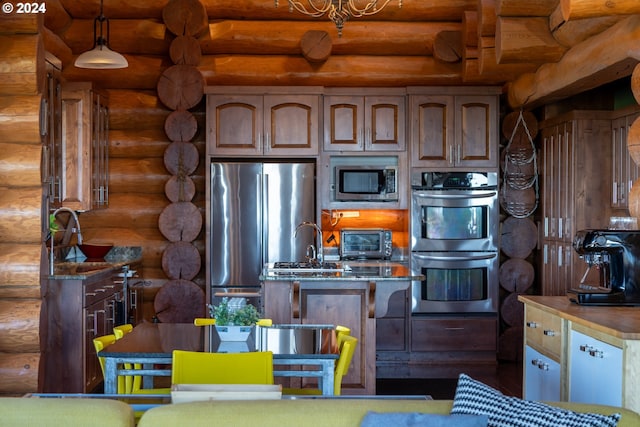 kitchen featuring appliances with stainless steel finishes, sink, rustic walls, and decorative light fixtures