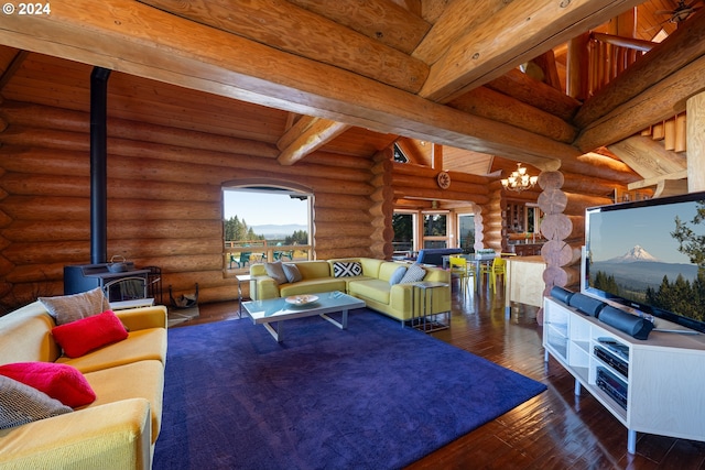 living room featuring log walls, dark wood-type flooring, a wood stove, beam ceiling, and an inviting chandelier