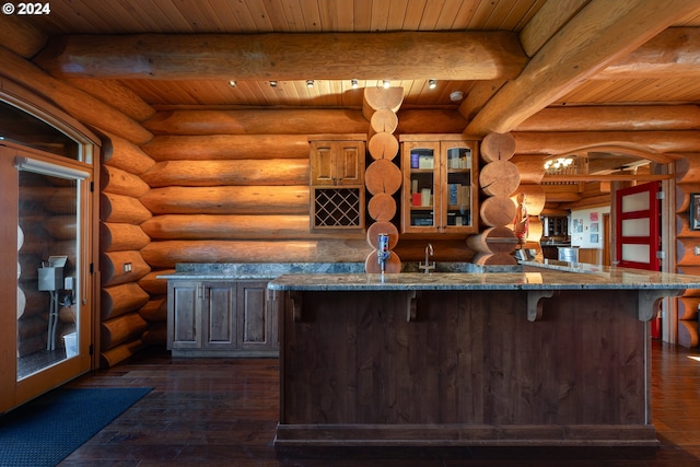 kitchen featuring beamed ceiling, dark wood-type flooring, stone countertops, rustic walls, and wooden ceiling