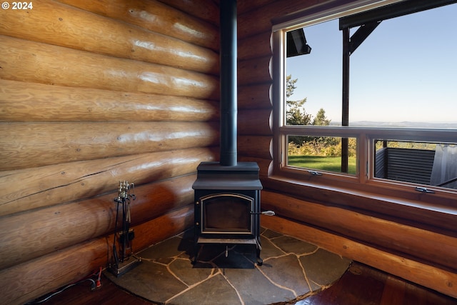 room details featuring a wood stove, wood-type flooring, and log walls