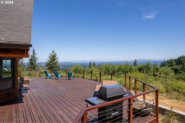 wooden deck featuring a mountain view and a grill