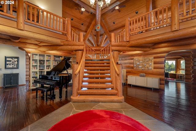 stairs featuring beam ceiling, log walls, high vaulted ceiling, and hardwood / wood-style flooring