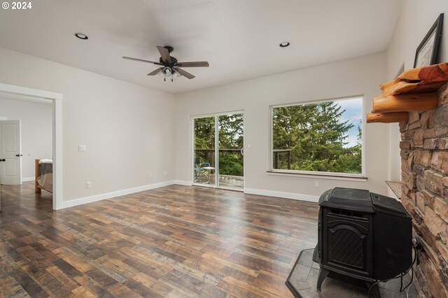 living room featuring ceiling fan, dark hardwood / wood-style flooring, and a wood stove