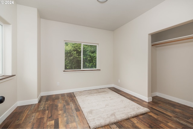 unfurnished bedroom with dark wood-style floors, a closet, and baseboards