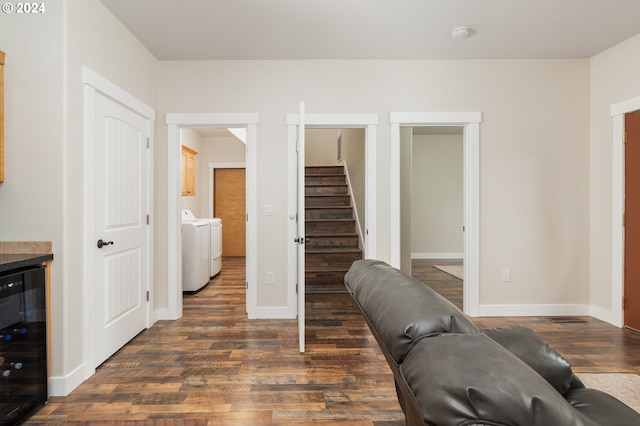 living area featuring beverage cooler, independent washer and dryer, dark wood-style floors, and baseboards