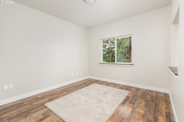 spare room with dark wood-style floors and baseboards