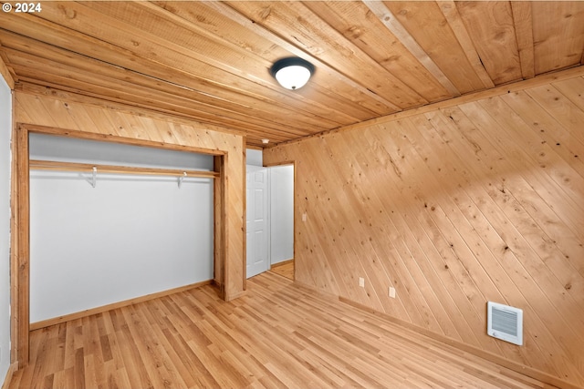 unfurnished bedroom featuring visible vents, wood finished floors, a closet, wood walls, and wood ceiling