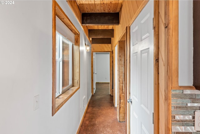 hallway with beam ceiling, wood ceiling, and concrete flooring