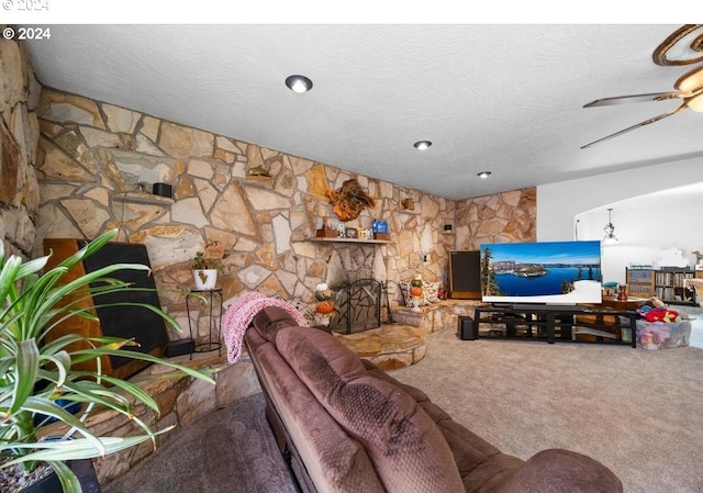 living room featuring a fireplace, a textured ceiling, carpet floors, and ceiling fan