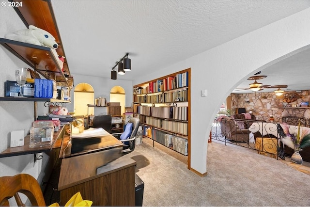 carpeted office featuring a fireplace, a textured ceiling, and ceiling fan